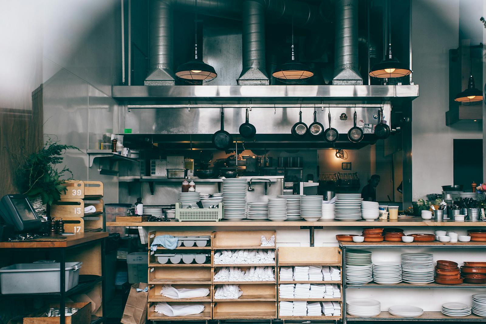 Commercial kitchen exhaust canopy and ductwork above a busy cook line