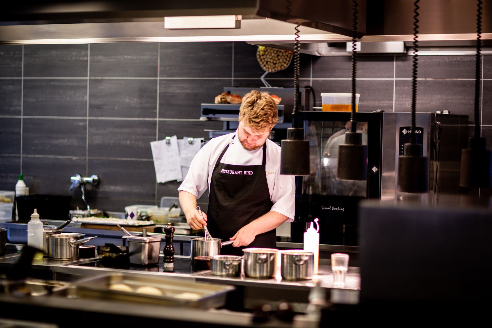 Chef working a service line beneath a stainless commercial extraction hood