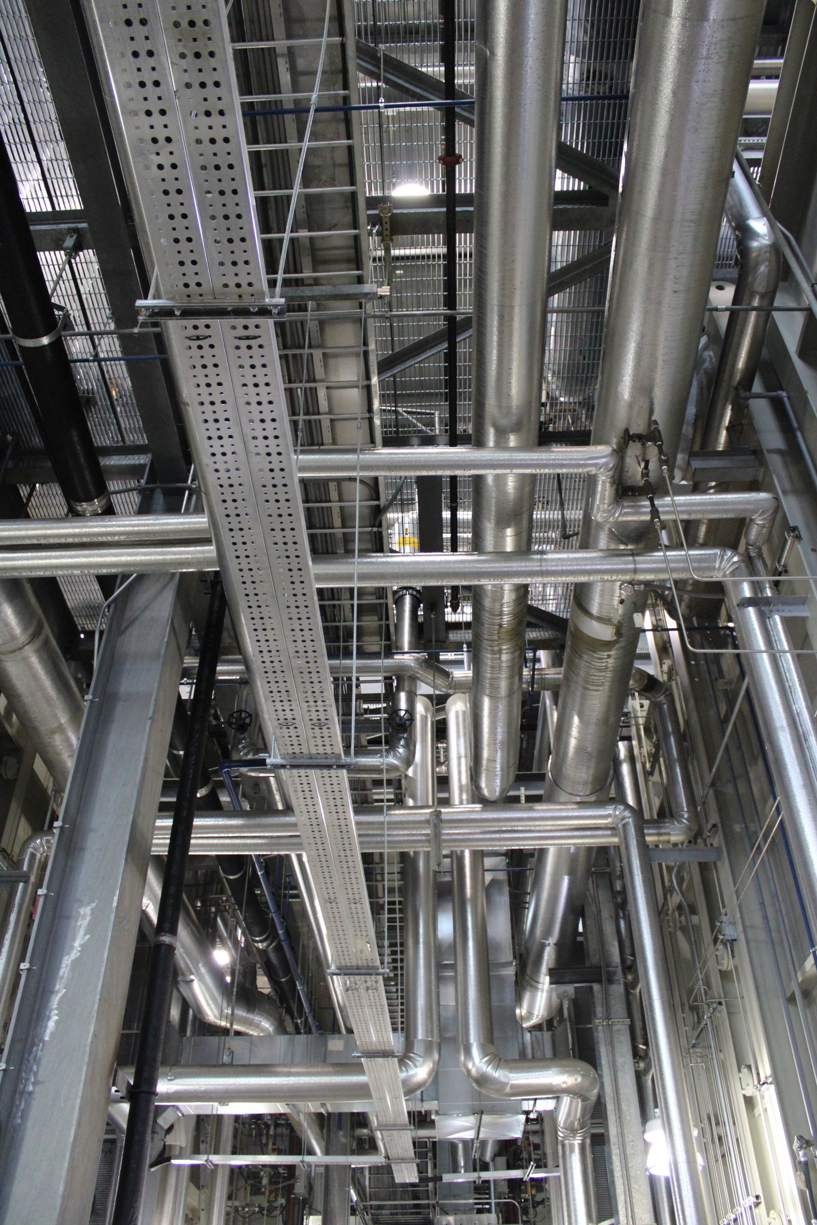 Stainless steel exhaust duct runs through a commercial plant room